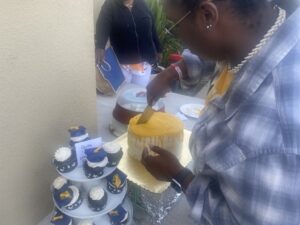 a woman holding a knife and cutting into the top of the yellow and white cake